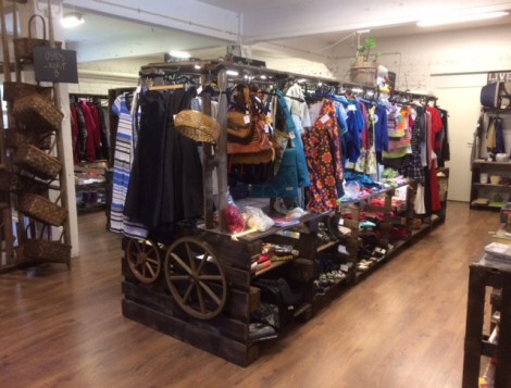 Kuvassa Kirpputori Vintikkeen liiketiloja Mänttä-Vilppulassa. Valokuva tyylikkäästä puisesta myyntihyllyköstä, joka täynnä erilaisia tavaroita ja vaatteita.