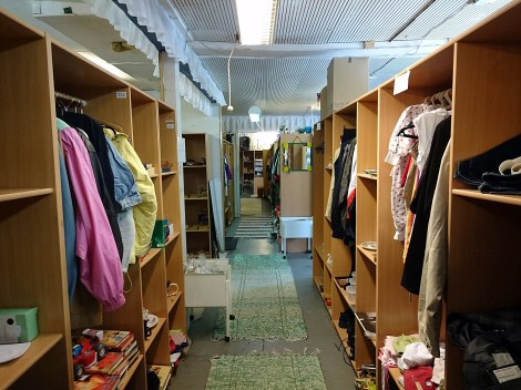 Käytävä, jonka molemmin puolin kirppis pöytiä täynnä vaatteita ja muita tavaroita, kuten kirjoja.