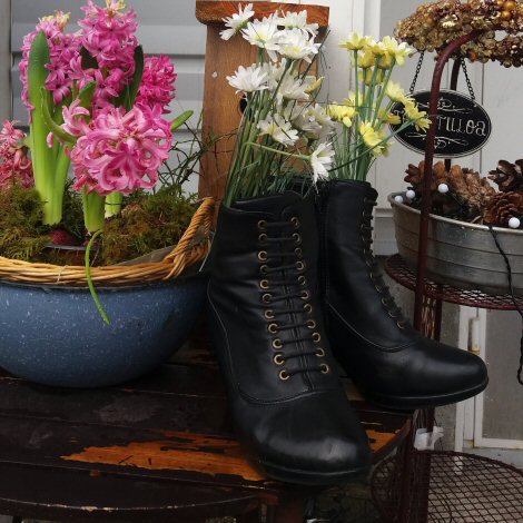 Valokuva naisten koristeellisista nahkakengistä kukkavaasien ja -koristeiden edessä.