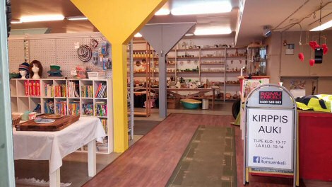 Vasemmalla valkoinen pöytä, oikealla kyltti, jossa lukee 'Kirppis auki'.
