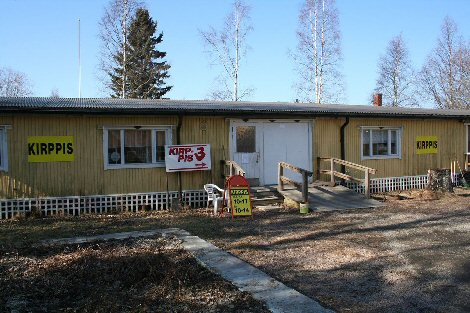 Valokuva Kirppis 3 -kirpparin julkisivusta. Kirppis sijaitsee yksikerroksisessa rakennuksessa.