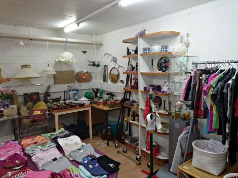 Kuvassa näytteitä Alajärven Kellarikirppiksen tavaravalikoimasta. Kuvassa Alajärven Kellarikirppiksen tavaravalikoimaa: vaatteita, koriste-esineitä, käyttötarpeita, valaisimia ym.