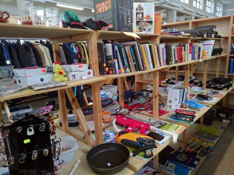Kirjoja, lehtiä, leluja ja kaikenlaista puisissa myyntihyllyissä.