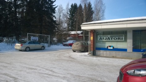 Ulkoa kuvattu Äijätorin liiketila oikealla ja parkkitilaa sen ympärillä.