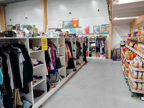 Leveä käytävä, jonka vasemmalla puolella valkoissia kirppishyllyköitä täynnä värikkäitä tavaroita.