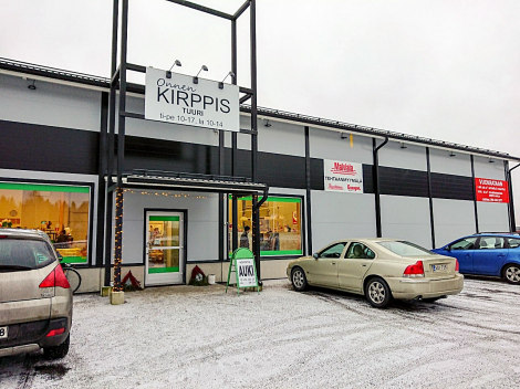 Valoisana talvipäivänä kuvattu OnnenKirppiksen julkisivu. Lunta maassa, taivas vitivalkoinen.