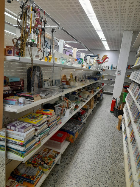 Värivalokuva myymäläkäytävästä, jossa käytävän molemmin puolin hyllyt täynnä erilaisia pienesineitä.