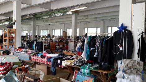 Valkoiseksi maalatussa hallissa runsaasti erilaisia myyntipaikkoja täynnä tavaroita.